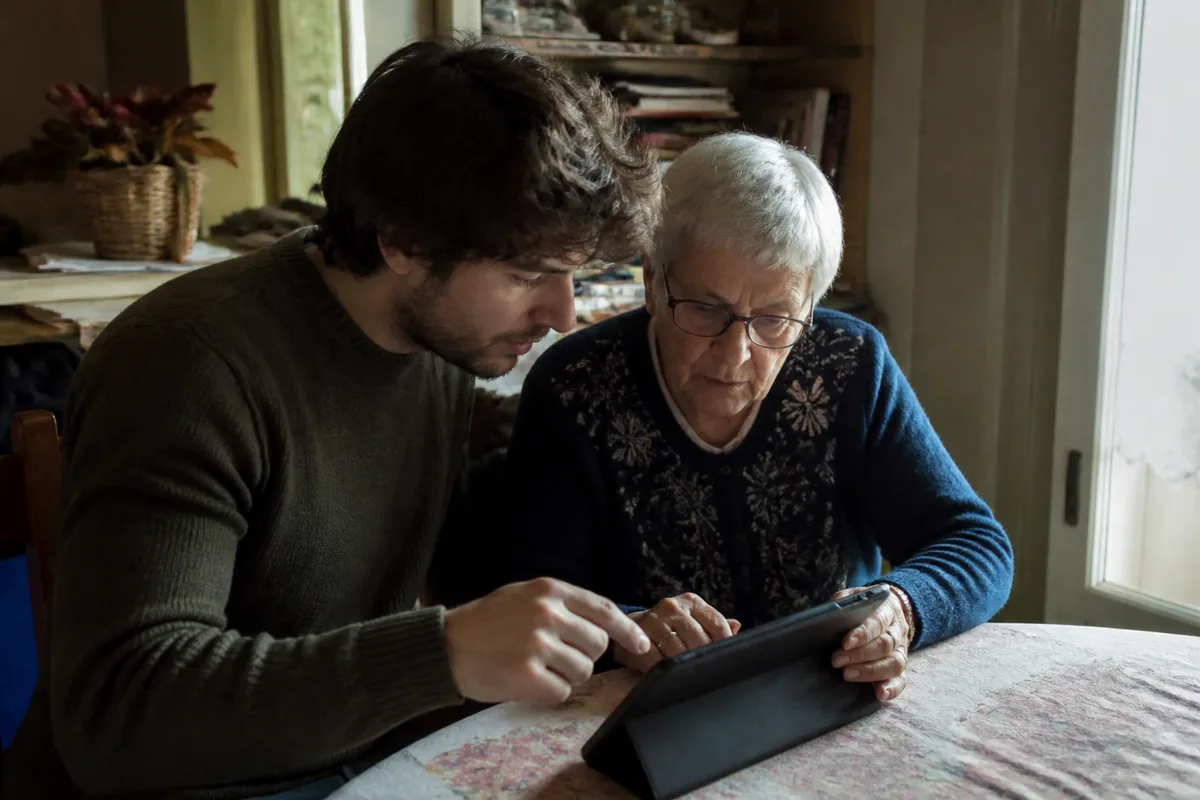 Senior utilisant une tablette avec un proche pour configurer une intelligence artificielle